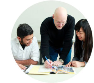 An English instructor works with two smiling international students